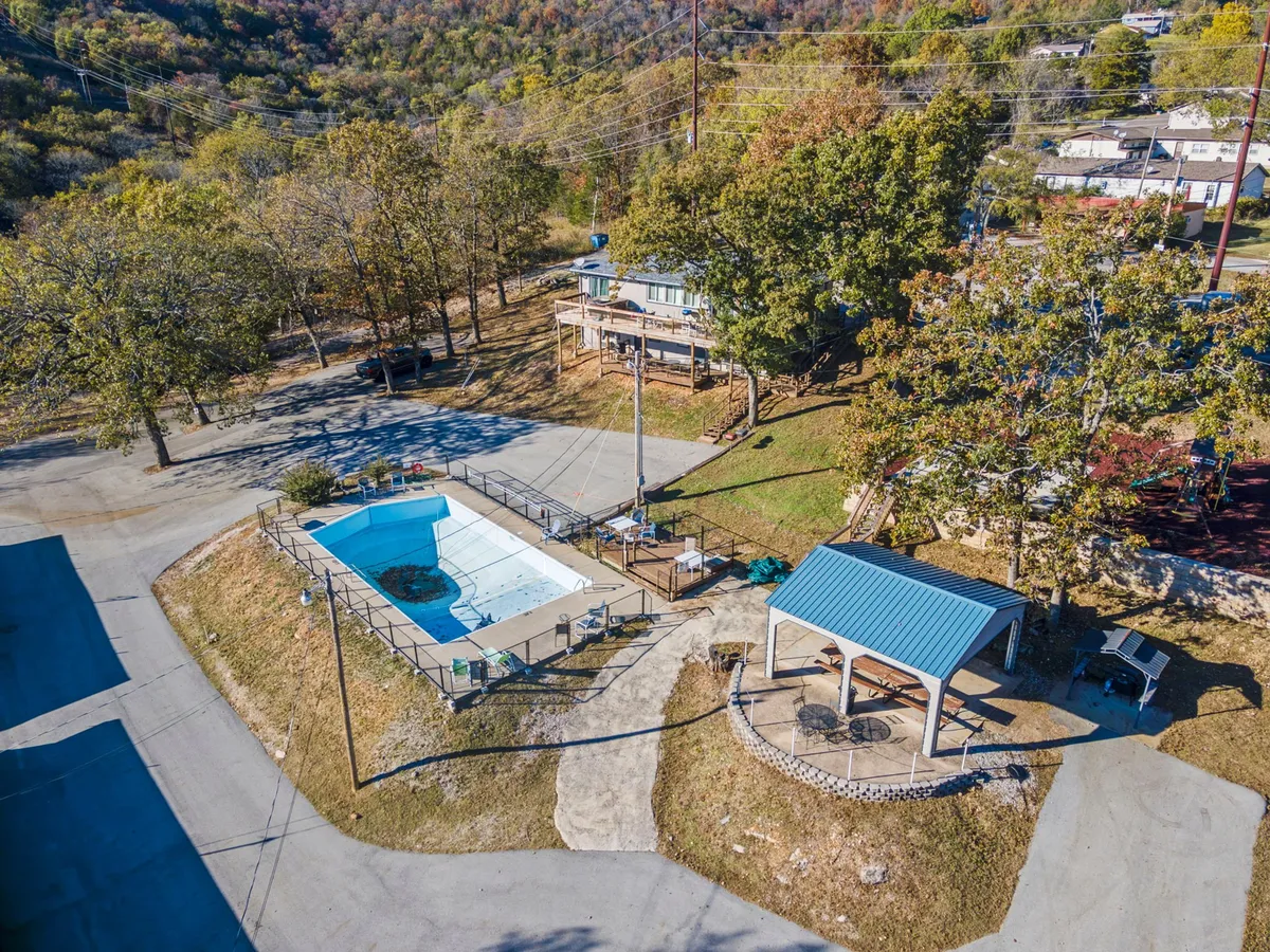 An inviting outdoor swimming pool is surrounded by a gazebo, outdoor seating areas, and mature trees. The space suggests both relaxation and social gatherings, offering guests a place to unwind after a day on the lake.