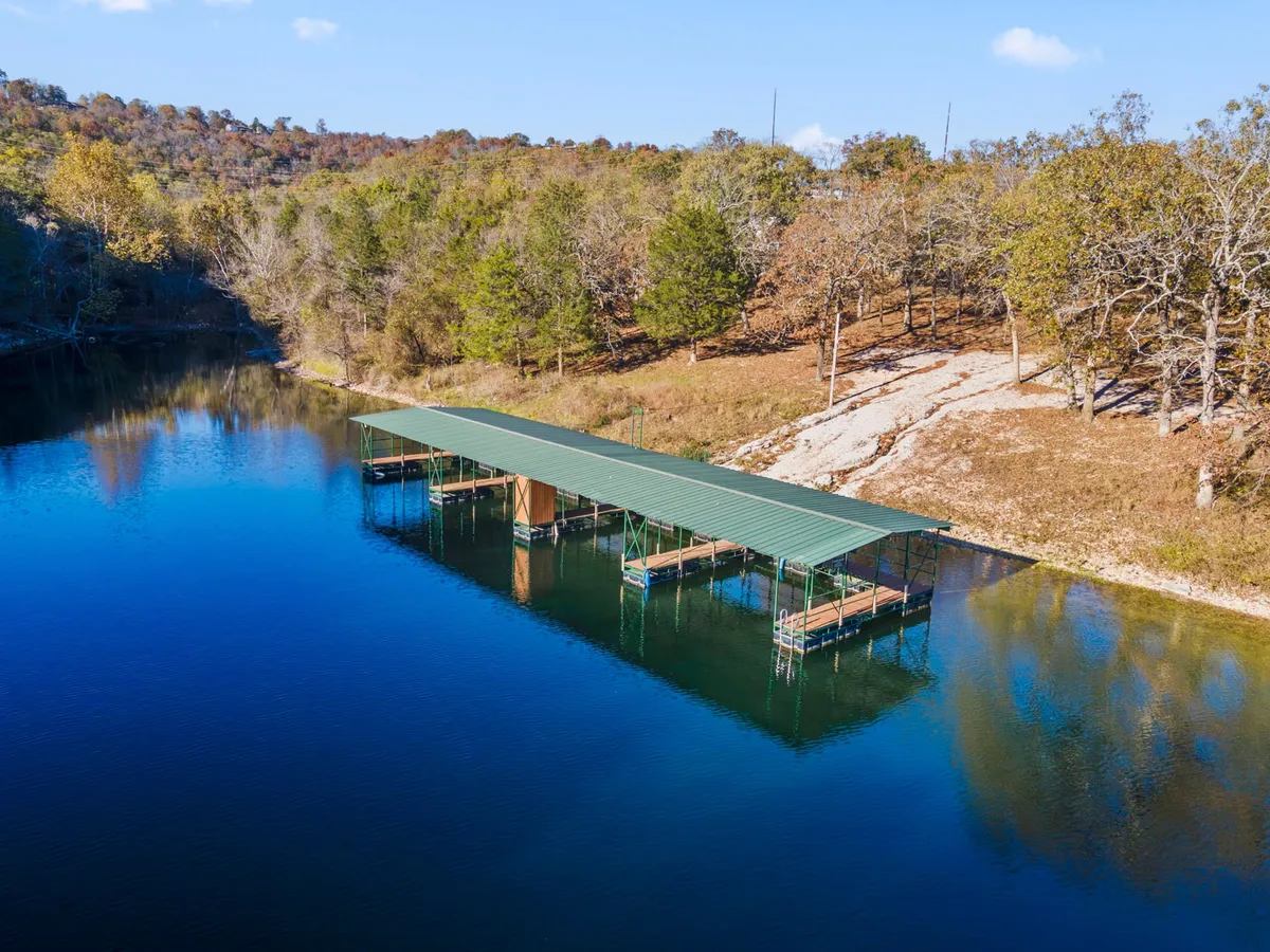 A peaceful dock stretches out over calm lake waters, surrounded by lush trees. It's an inviting spot for a sunset stroll, hand-in-hand moments, or launching a boat for a romantic ride.