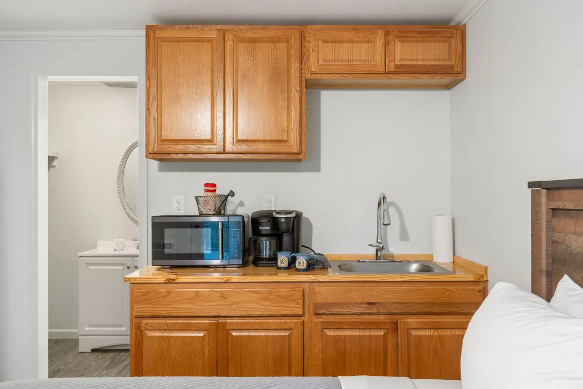 A close-up view of the kitchenette area, featuring a microwave, coffee maker, and sink. The setup is compact but practical, with storage and preparation space for snacks, coffee, and light meals.