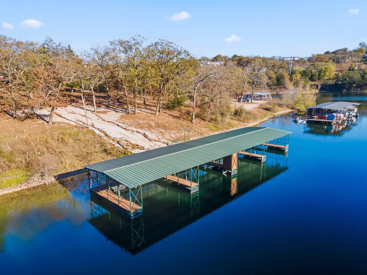 A peaceful lakeside scene with a well-maintained boat dock extending over still water, framed by trees. The setting suggests opportunities for fishing, launching boats, and enjoying tranquil moments by the water's edge.